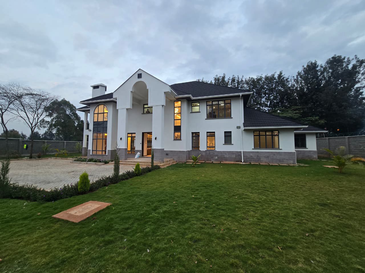 Completed two-storey private home at dusk, finished in white render with a dark tiled roof