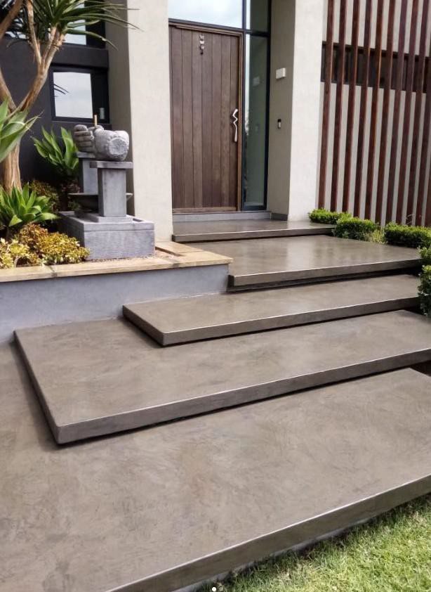 Broad micro-cement entrance steps leading to a timber front door, finished as one seamless surface